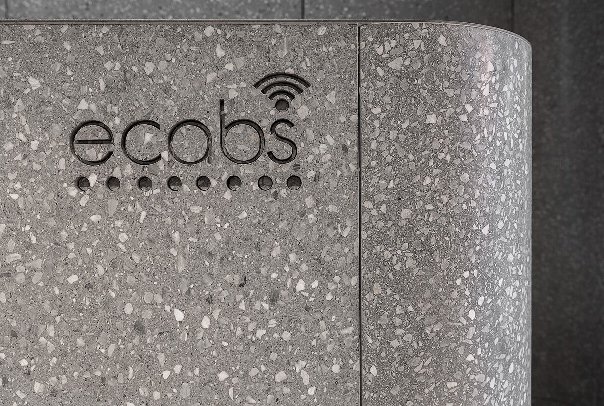 Detailed close-up of the terrazzo-clad Ecabs reception desk showing the logo engraved into the curved surface, highlighting the honed finish and aggregate texture.